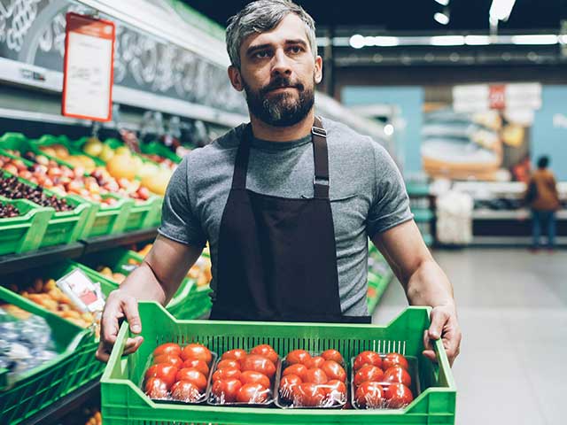 Grocery service worker in Cincinnati stocking produce to serve customers