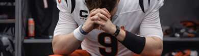 Joe Burrow sits in the locker room with his head down after a game, wearing a Cincinnati Bengals uniform