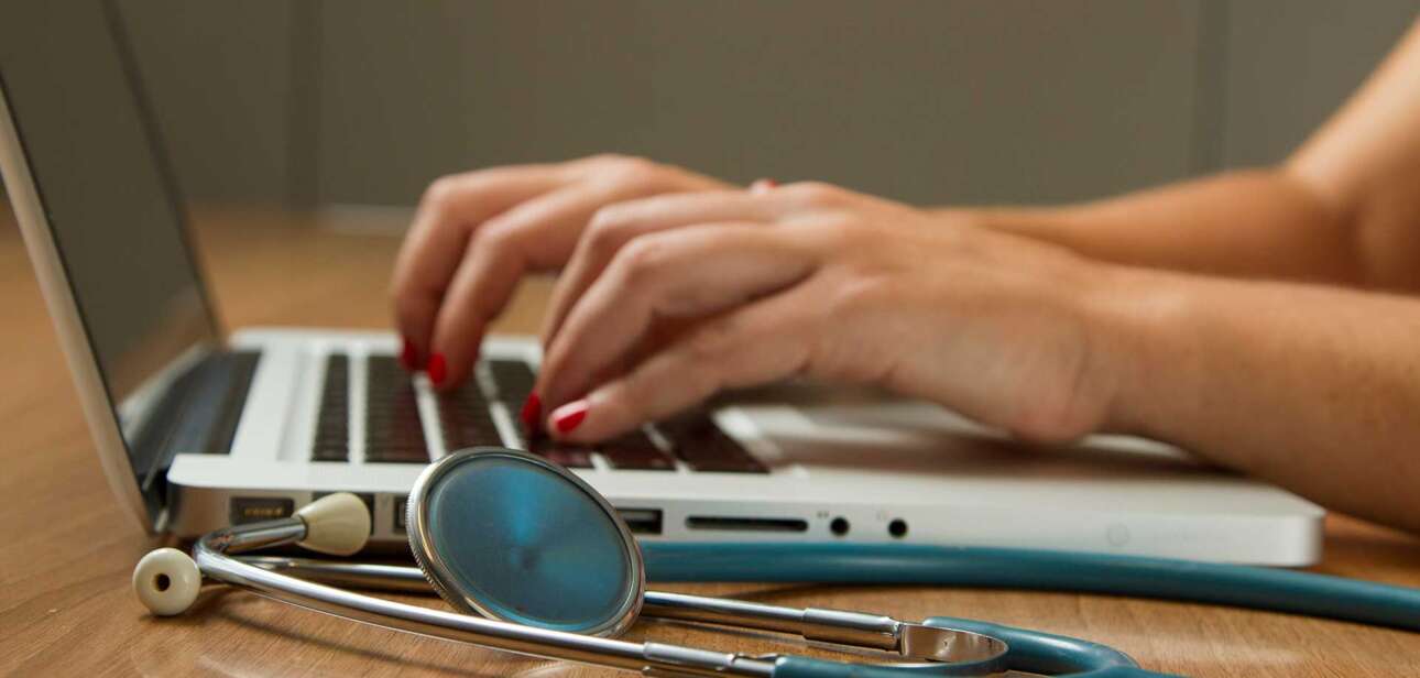 Senior accessing medical record portals on a laptop to manage online medical records