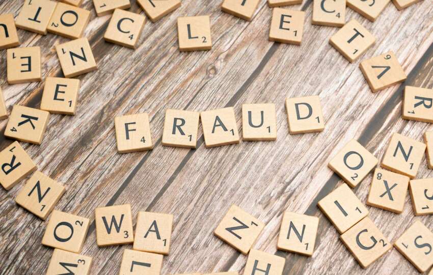 Scattered wooden letter tiles on a table spelling out words like FRAUD, NONPROFIT, TRUST, and LIES, representing concerns over nonprofit fraud and transparency in Cincinnati