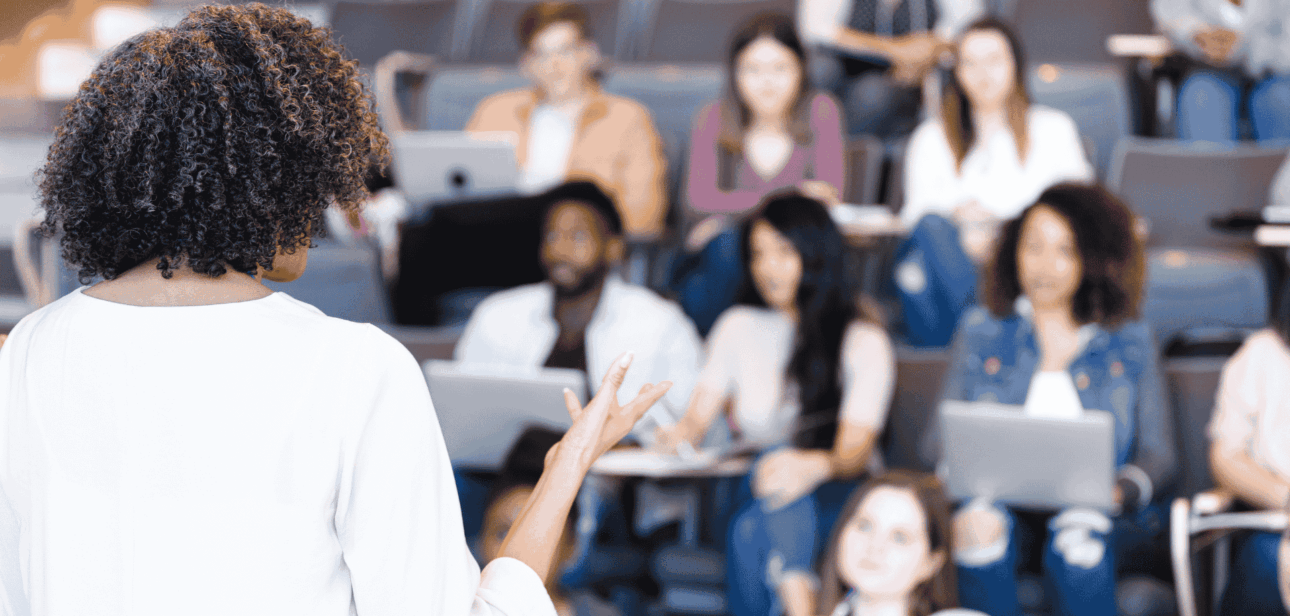 A female professor lecturing to a diverse group of students in a university classroom, illustrating education topics for Ohio Senate Bill 1.