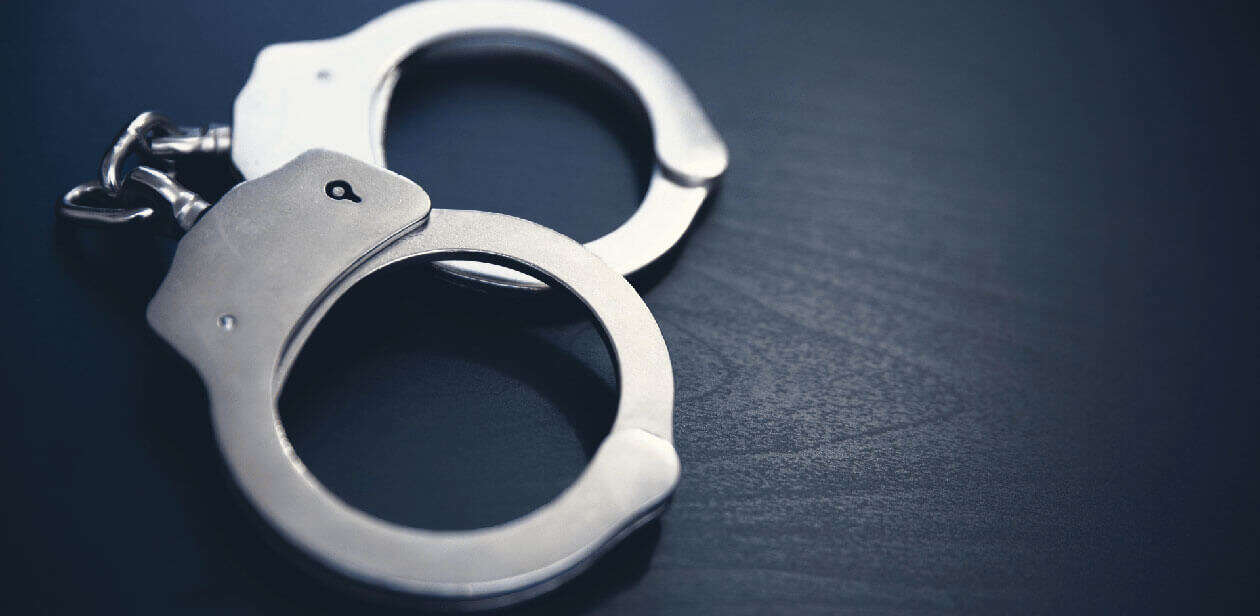 Silver handcuffs resting on a dark wooden surface, representing the reduction in violent crime across Ohio in 2025.