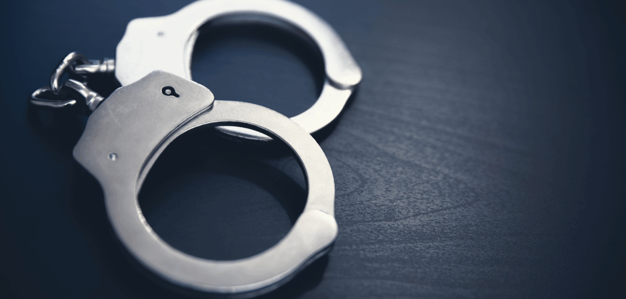 Silver handcuffs resting on a dark wooden surface, representing the reduction in violent crime across Ohio in 2025.