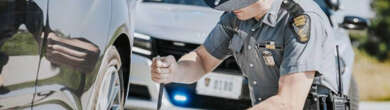 Ohio State Highway Patrol trooper checking a vehicle's tire during a roadside stop, to show their 2025 holiday enforcement blitz.