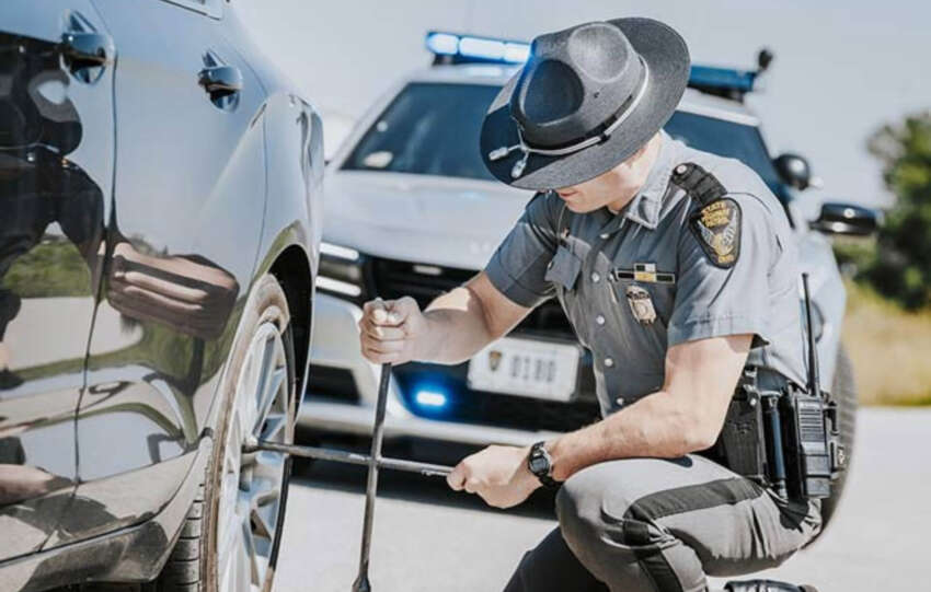Ohio State Highway Patrol trooper checking a vehicle's tire during a roadside stop, to show their 2025 holiday enforcement blitz.