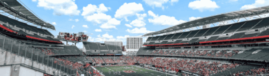 Wide interior view of Paycor Stadium in Cincinnati on a sunny day, showing the seating bowl and open-air design.