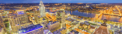 High-angle twilight view of the Cincinnati skyline with illuminated skyscrapers, the Great American Tower, and the Ohio River in the background.