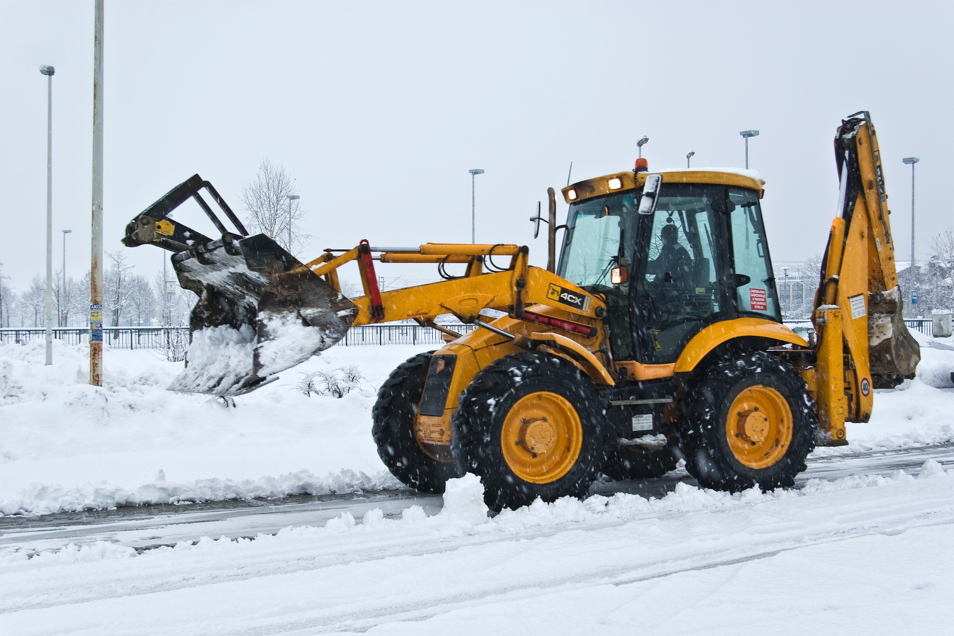 This image illustrates a yellow snow plow clearing roads in Cincinnati, Ohio, during winter weather causing school closings.