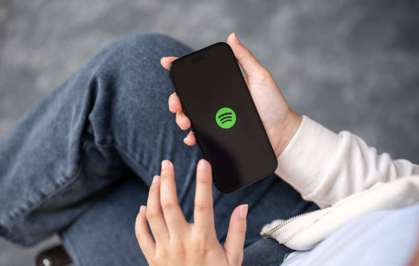 Person holding a smartphone with the Spotify app logo, illustrating the release of Spotify Wrapped 2025.