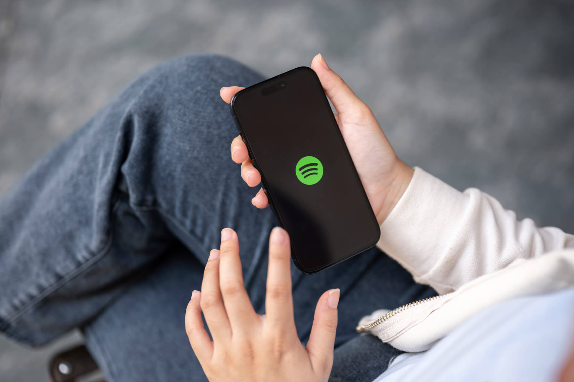 Person holding a smartphone with the Spotify app logo, illustrating the release of Spotify Wrapped 2025.