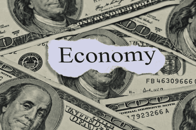 A collage of US dollar bills with the word "Economy" printed on a torn piece of paper in the center.