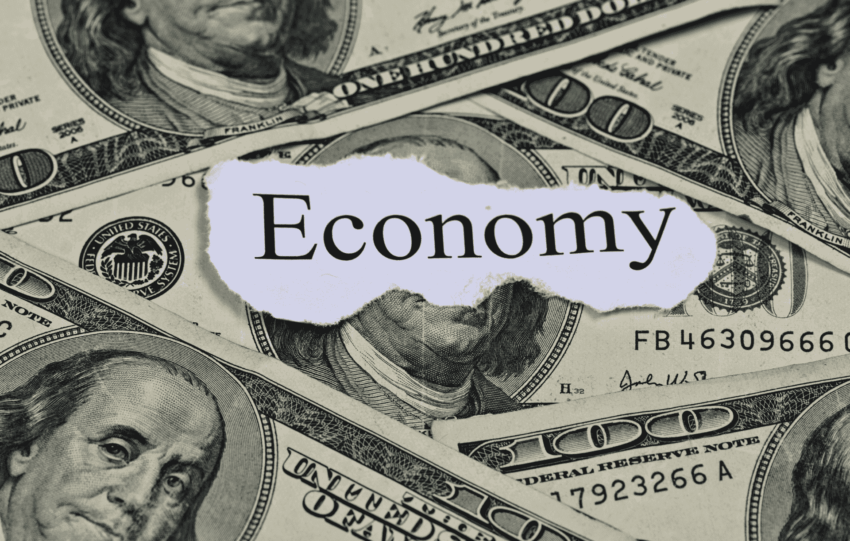 A collage of US dollar bills with the word "Economy" printed on a torn piece of paper in the center.