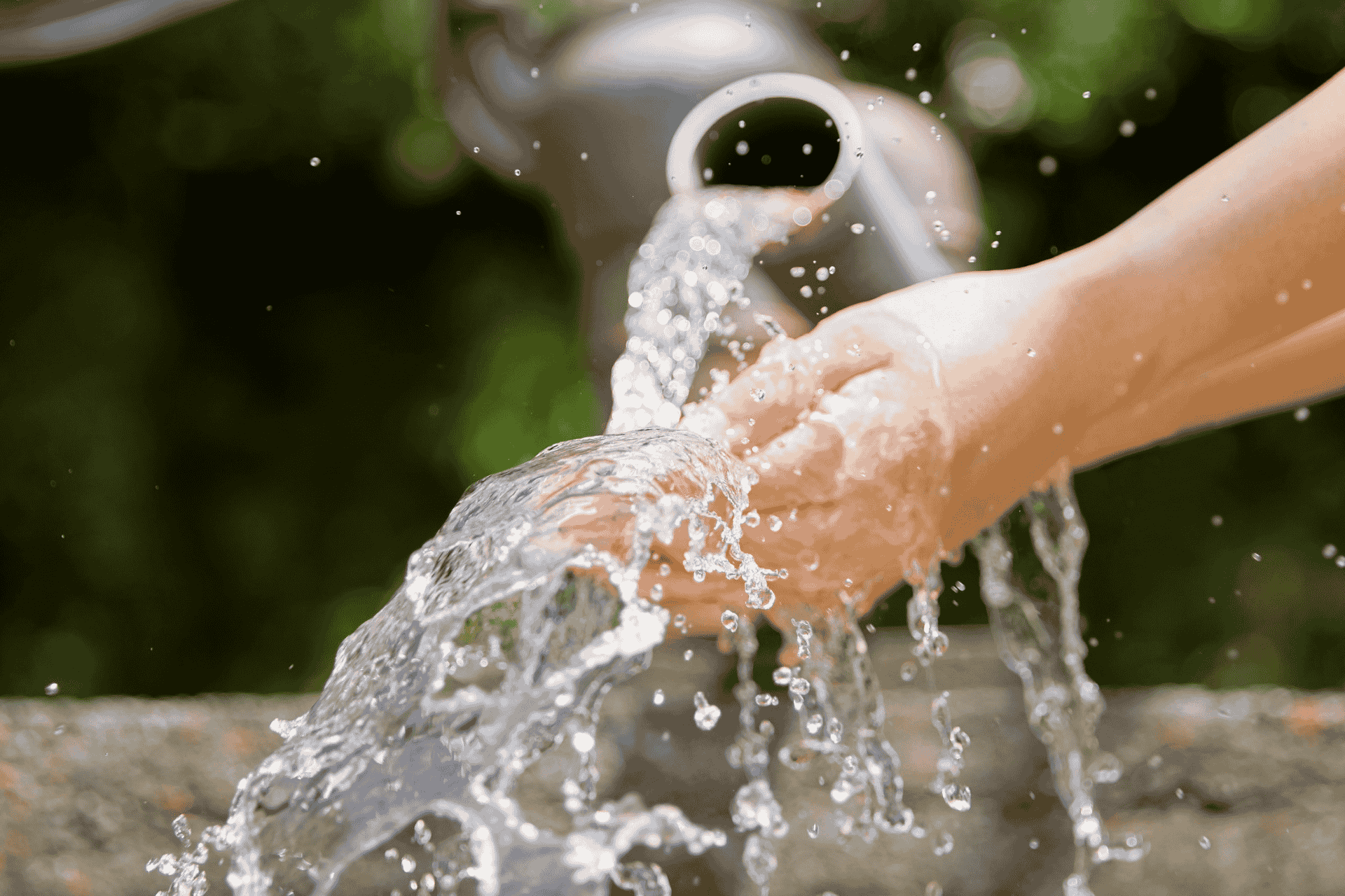 A close-up of hands cupping fresh running water from an outdoor tap, illustrating the surge in water demand.