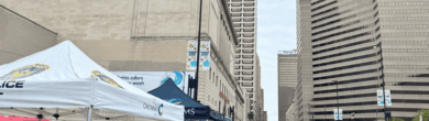 Large crowd in the City of Cincinnati during the Taste of Cincinnati 2025 featuring local police booths and downtown skyscrapers.