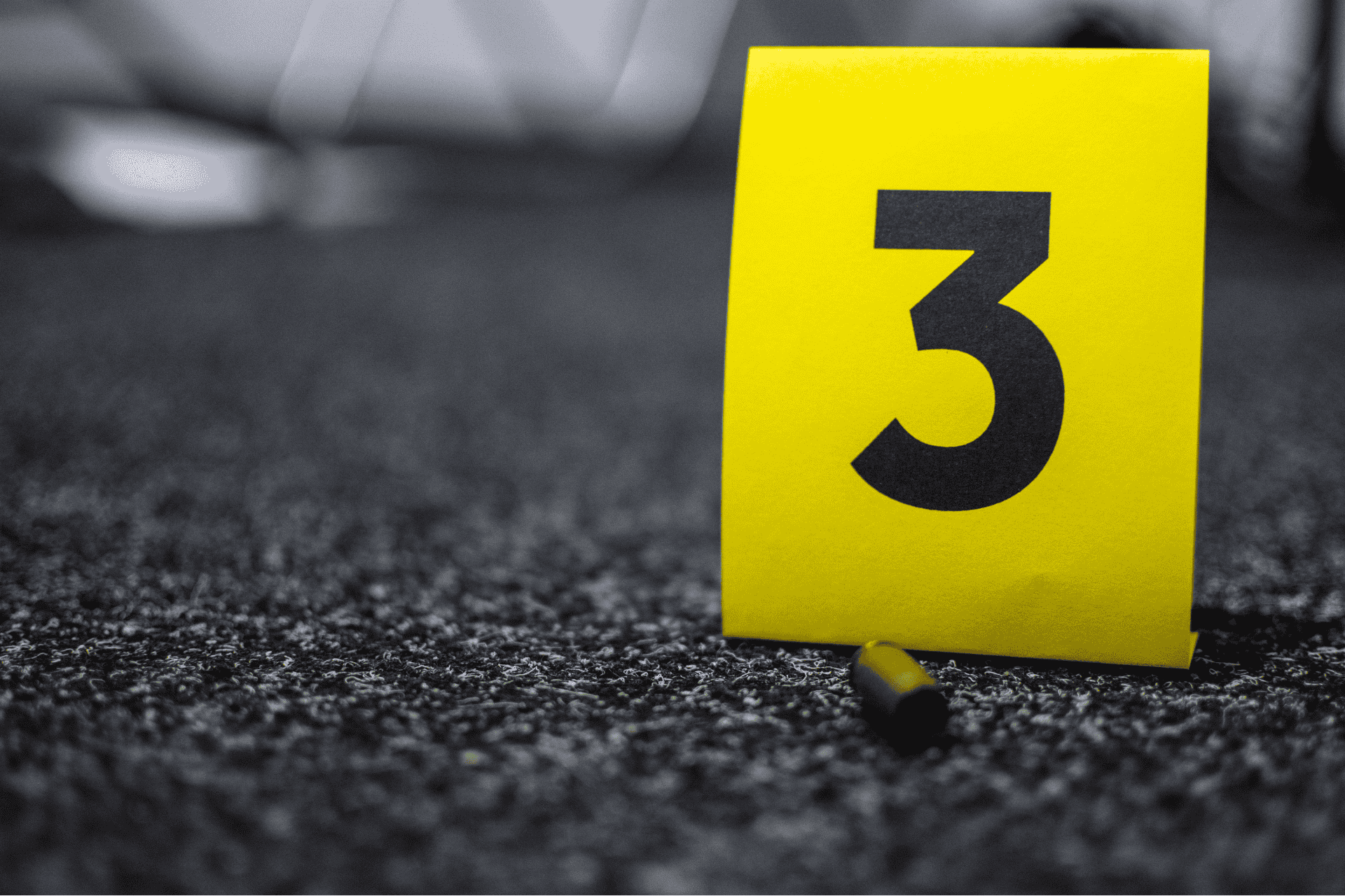 Yellow evidence marker labeled with the number 3 on dark asphalt.