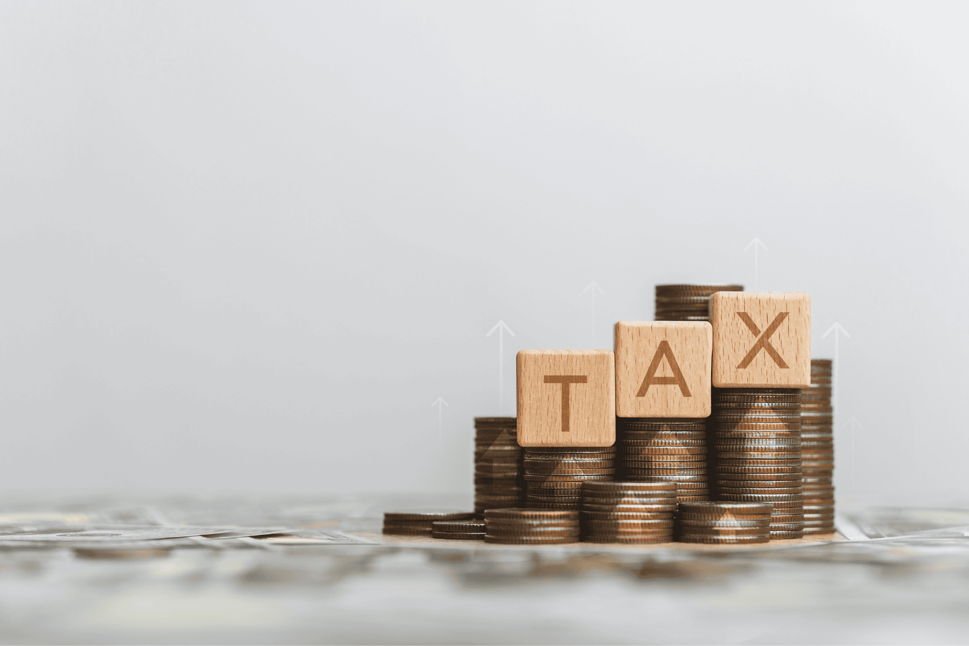 Stack of coins with wooden blocks spelling TAX and an upward arrow, representing the proposed Cincinnati income tax increase for public safety funding.