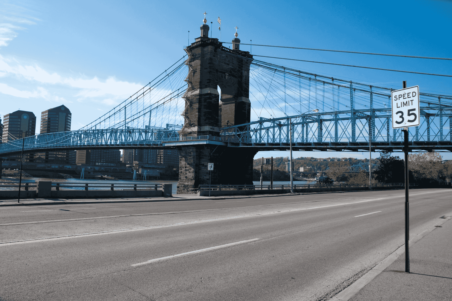 A view of the John A. Roebling Suspension Bridge in Cincinnati with a paved walkway and blue sky.