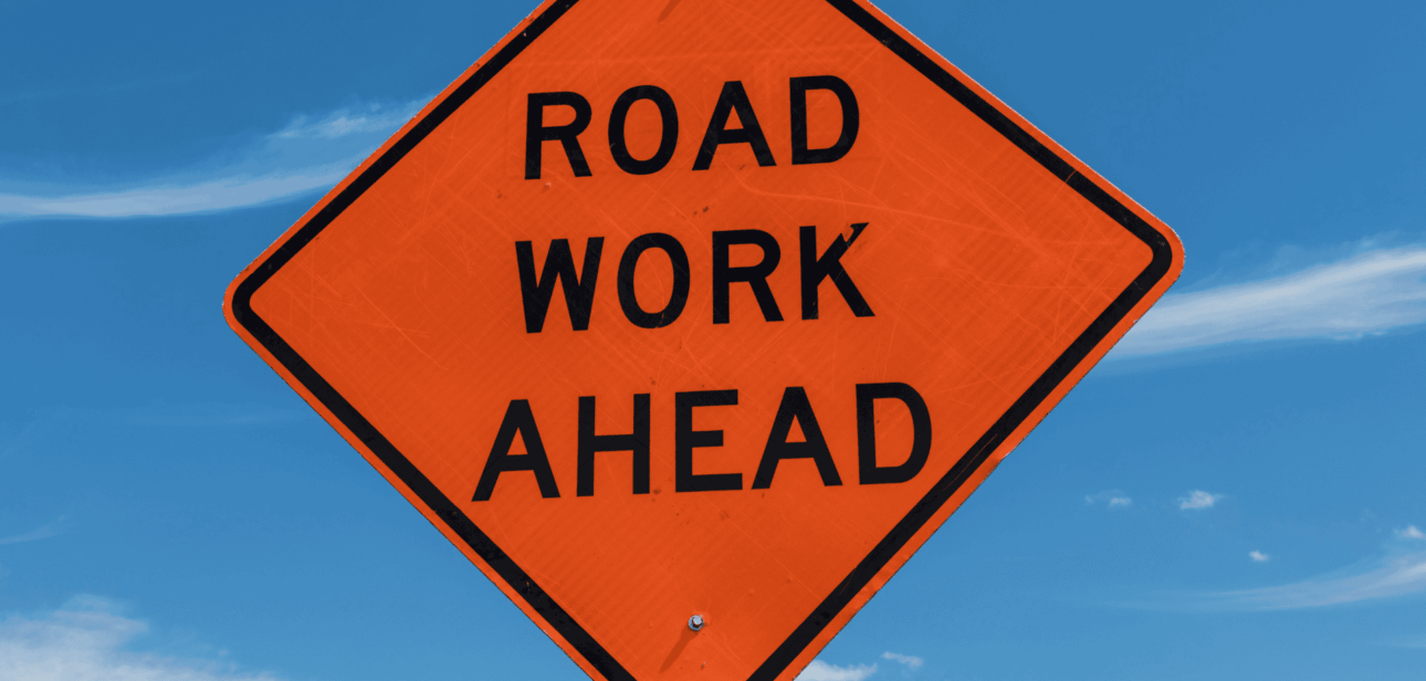 An orange diamond-shaped "Road Work Ahead" sign against a blue sky, illustrating the Fourth Street Bridge closure in Cincinnati.