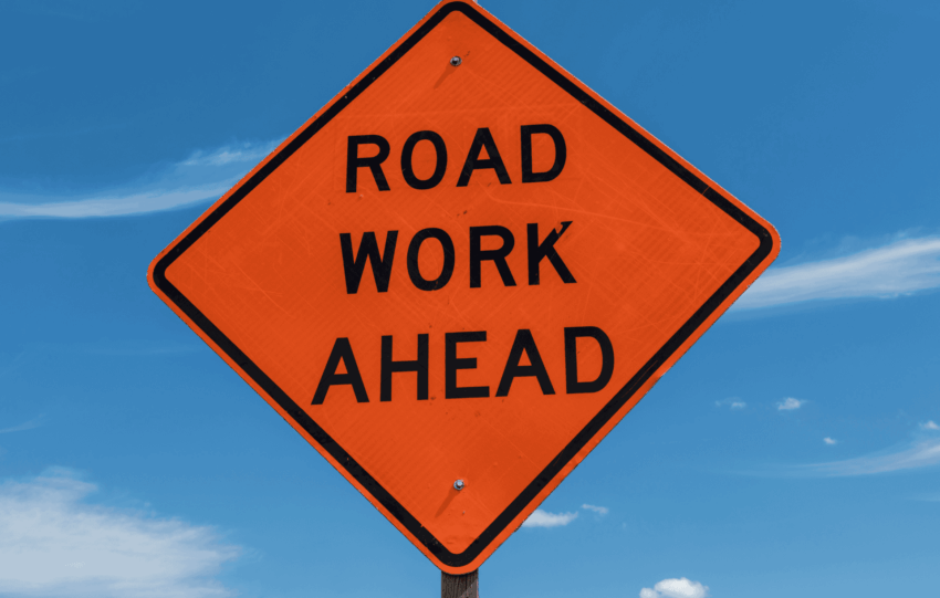 An orange diamond-shaped "Road Work Ahead" sign against a blue sky, illustrating the Fourth Street Bridge closure in Cincinnati.