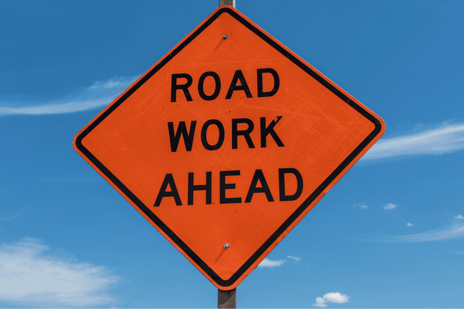 An orange diamond-shaped "Road Work Ahead" sign against a blue sky, illustrating the Fourth Street Bridge closure in Cincinnati.