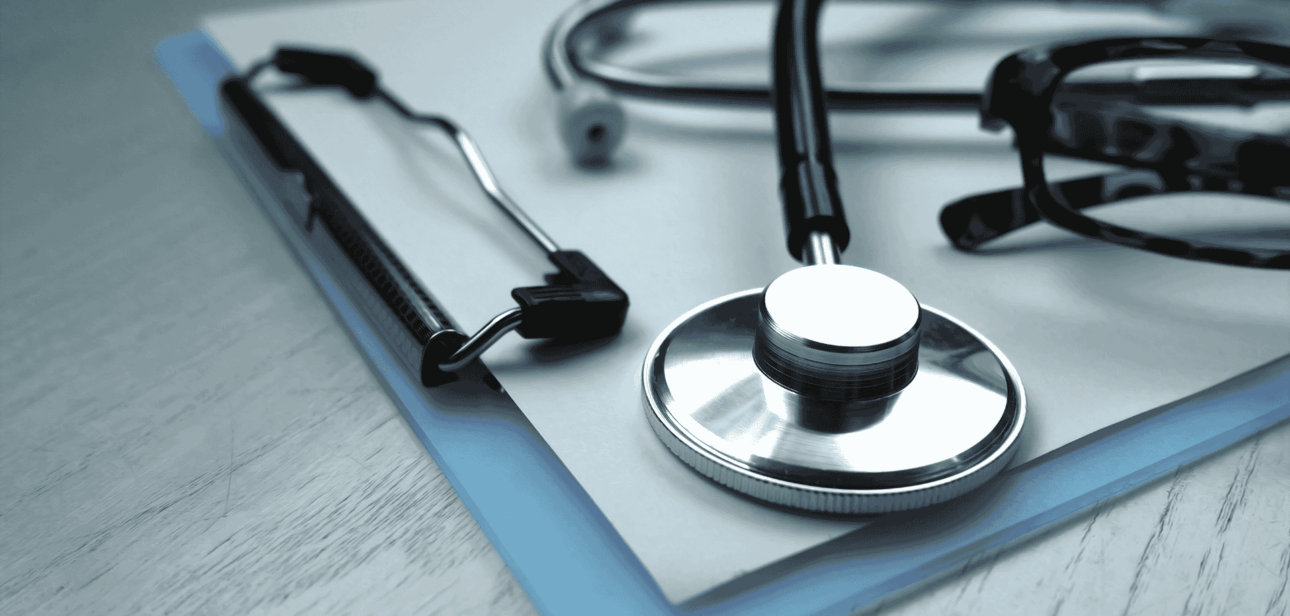 A stethoscope resting on a blue clipboard on a wooden desk, representing healthcare workers Cleveland at NEON clinics.