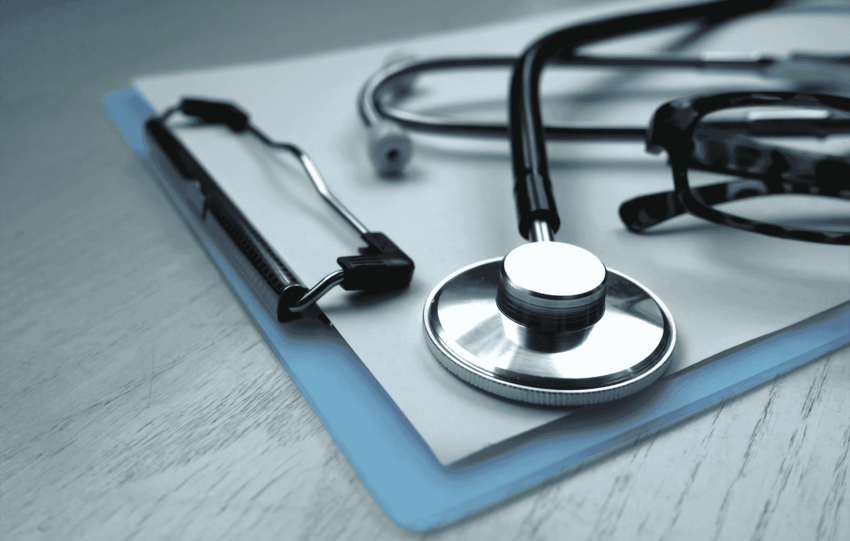 A stethoscope resting on a blue clipboard on a wooden desk, representing healthcare workers Cleveland at NEON clinics.