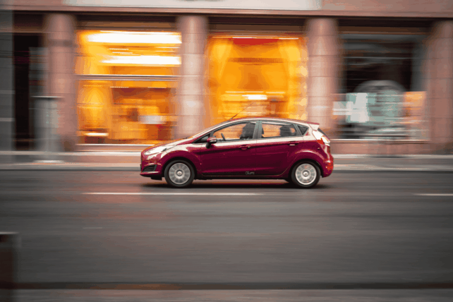 Red car speeding on a city street with motion blur, illustrating the crackdown on illegal street racing in Kentucky.