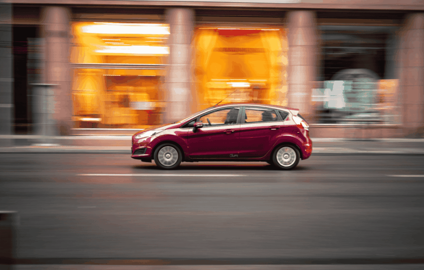 Red car speeding on a city street with motion blur, illustrating the crackdown on illegal street racing in Kentucky.