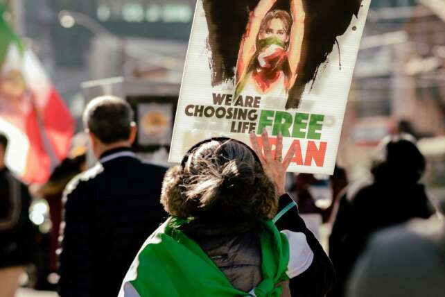 Demonstrators gather during protests in Iran, holding signs and flags as nationwide unrest challenges the government.