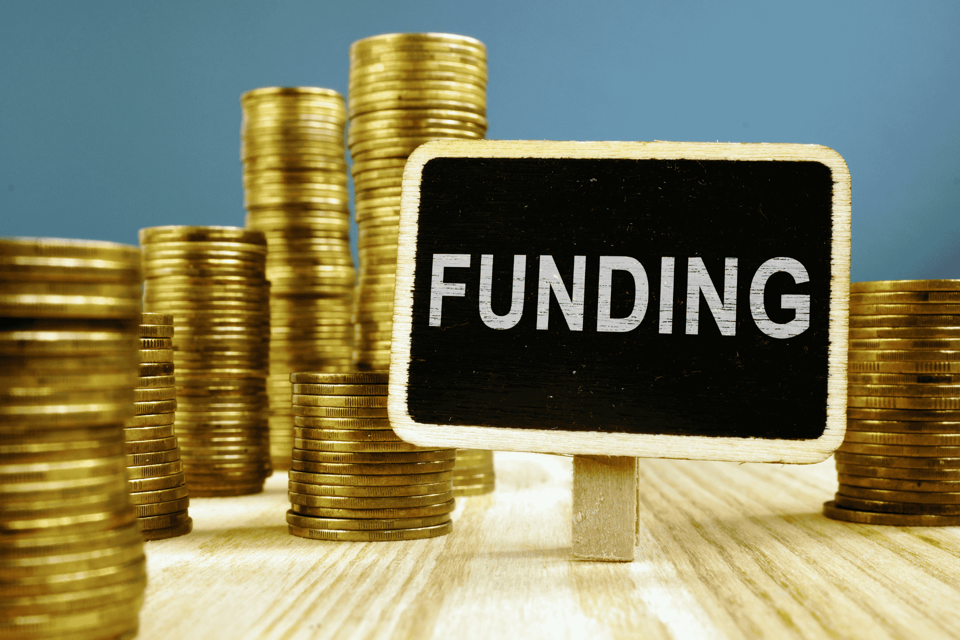 Stacks of gold coins arranged next to a small chalkboard sign reading "Funding," illustrating public safety budget discussions in Cincinnati.
