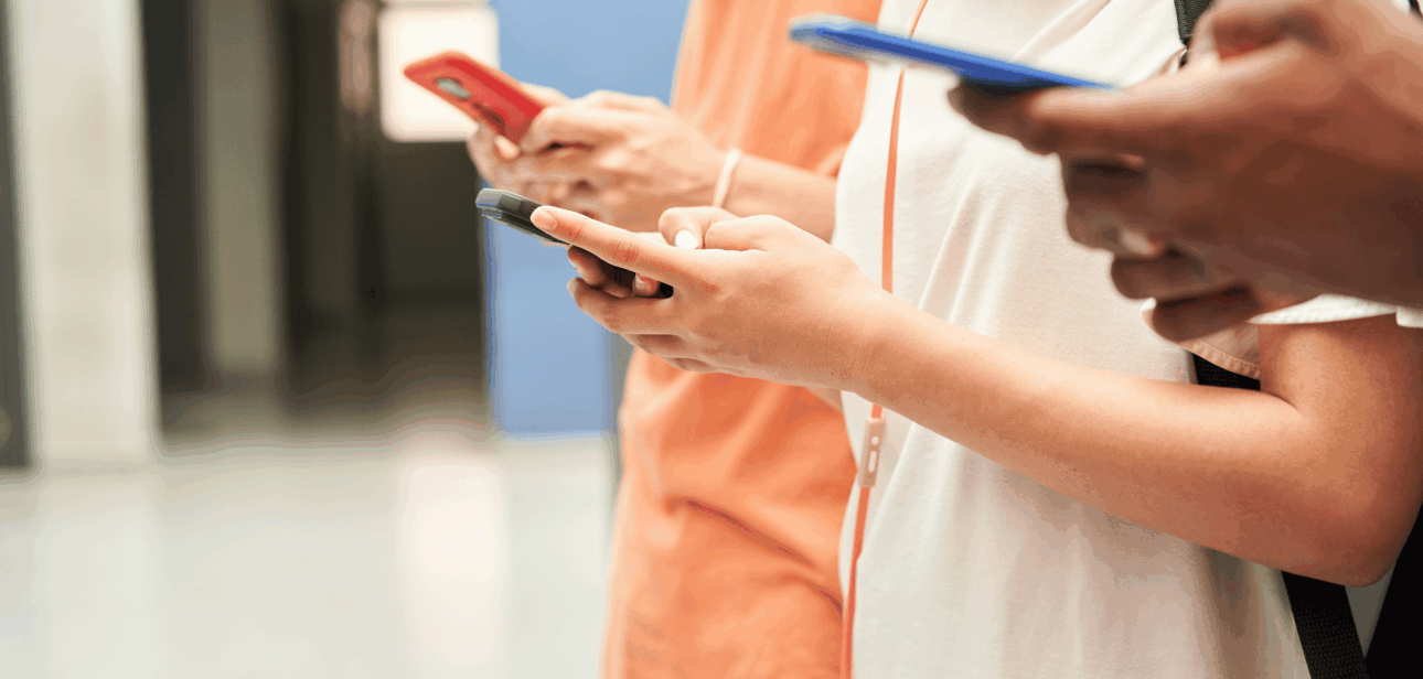 Students standing in a school hallway looking at their smartphones, illustrating the impact of the new Ohio school phone policy restrictions.