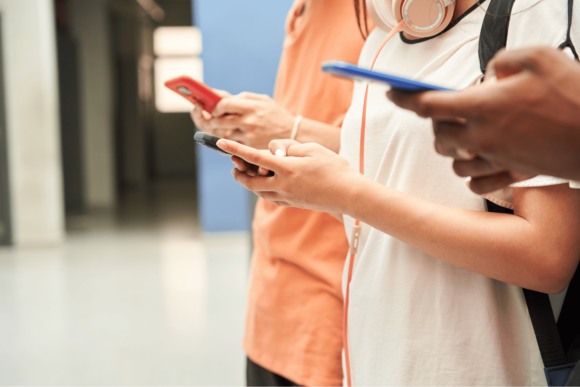 Students standing in a school hallway looking at their smartphones, illustrating the impact of the new Ohio school phone policy restrictions.