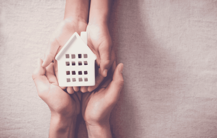 Hands holding a small white model house, symbolizing a seasonal homeless shelter in Cleveland, Ohio.