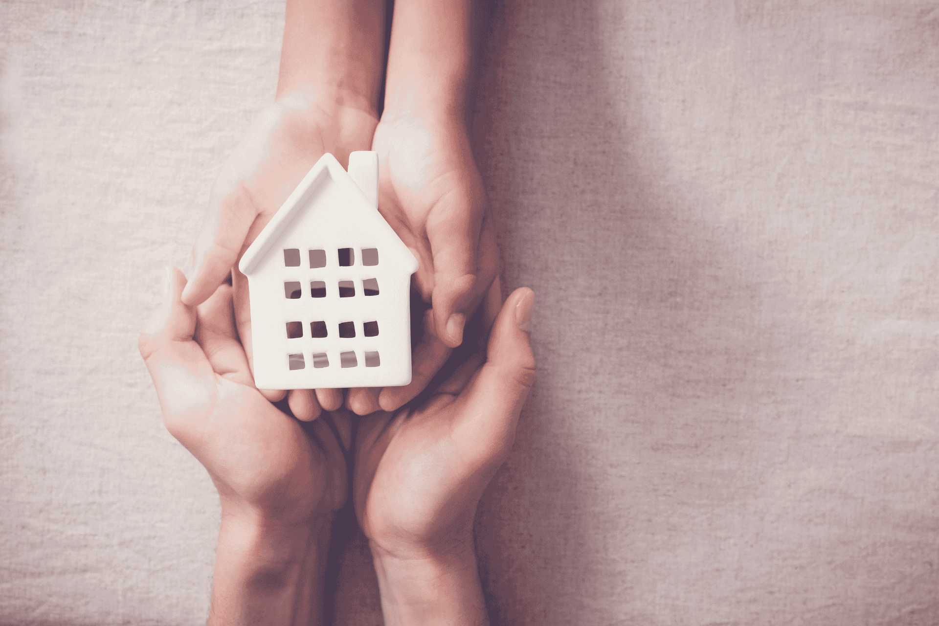 Hands holding a small white model house, symbolizing a seasonal homeless shelter in Cleveland, Ohio.