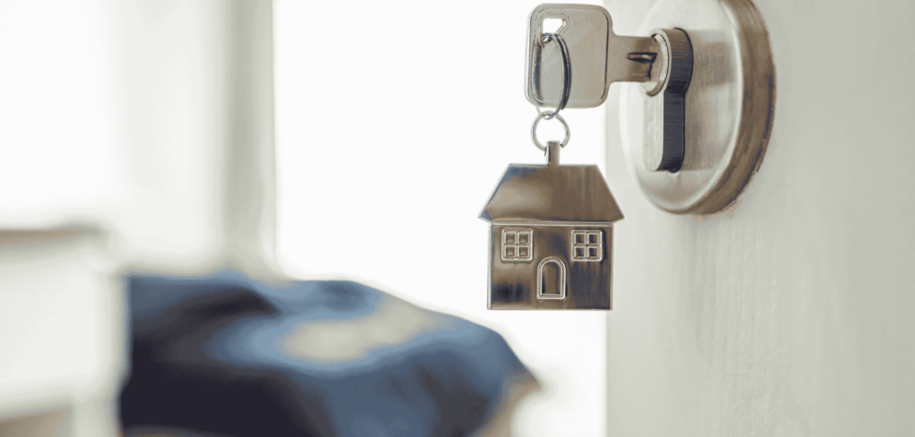 A key in a door lock with a house-shaped keychain, illustrating short-term rental safety and security in Ohio.
