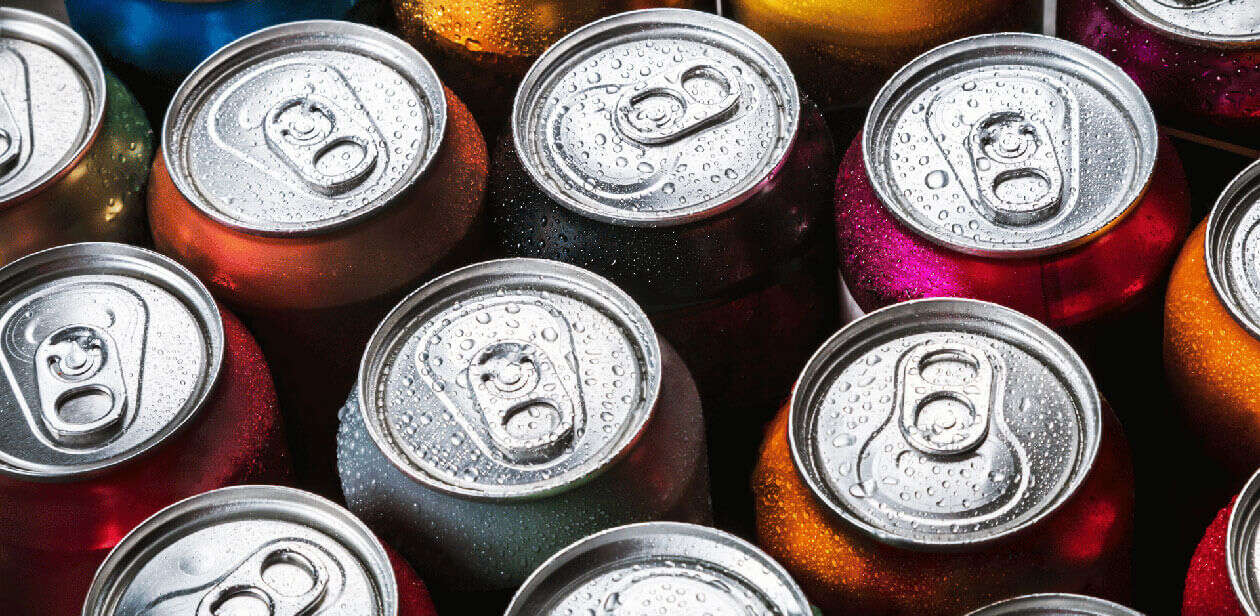 A top-down view of several colorful soda cans grouped together, illustrating sugar-sweetened beverages subject to SNAP ban proposals.
