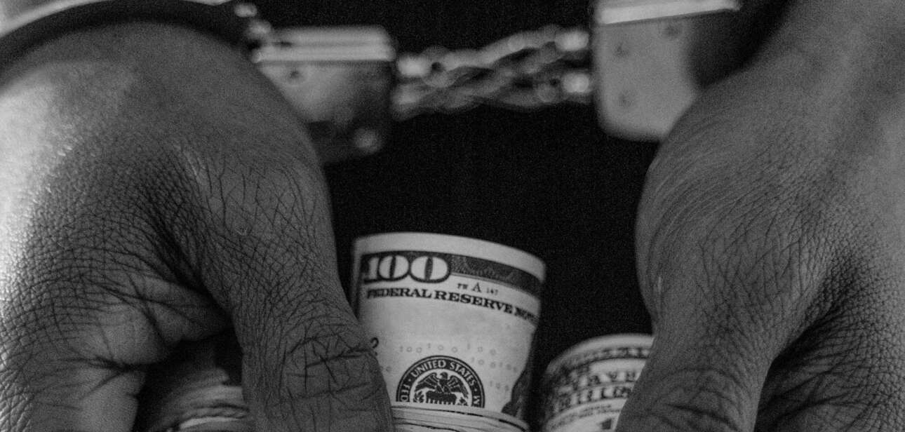 A grainy black and white meme photograph depicting a person handcuffed holding cash to represent somali fraud ohio