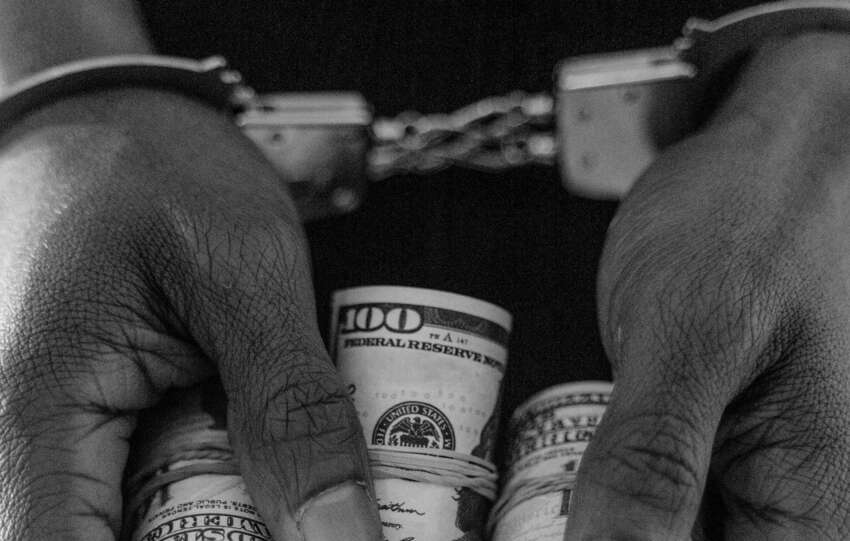 A grainy black and white meme photograph depicting a person handcuffed holding cash to represent somali fraud ohio