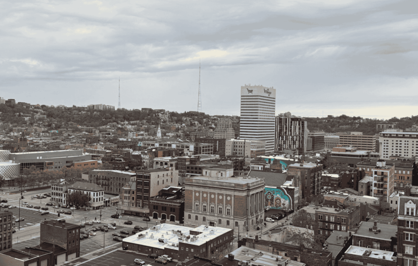 A sprawling view of the Cincinnati skyline and Over-the-Rhine neighborhood under a cloudy sky.
