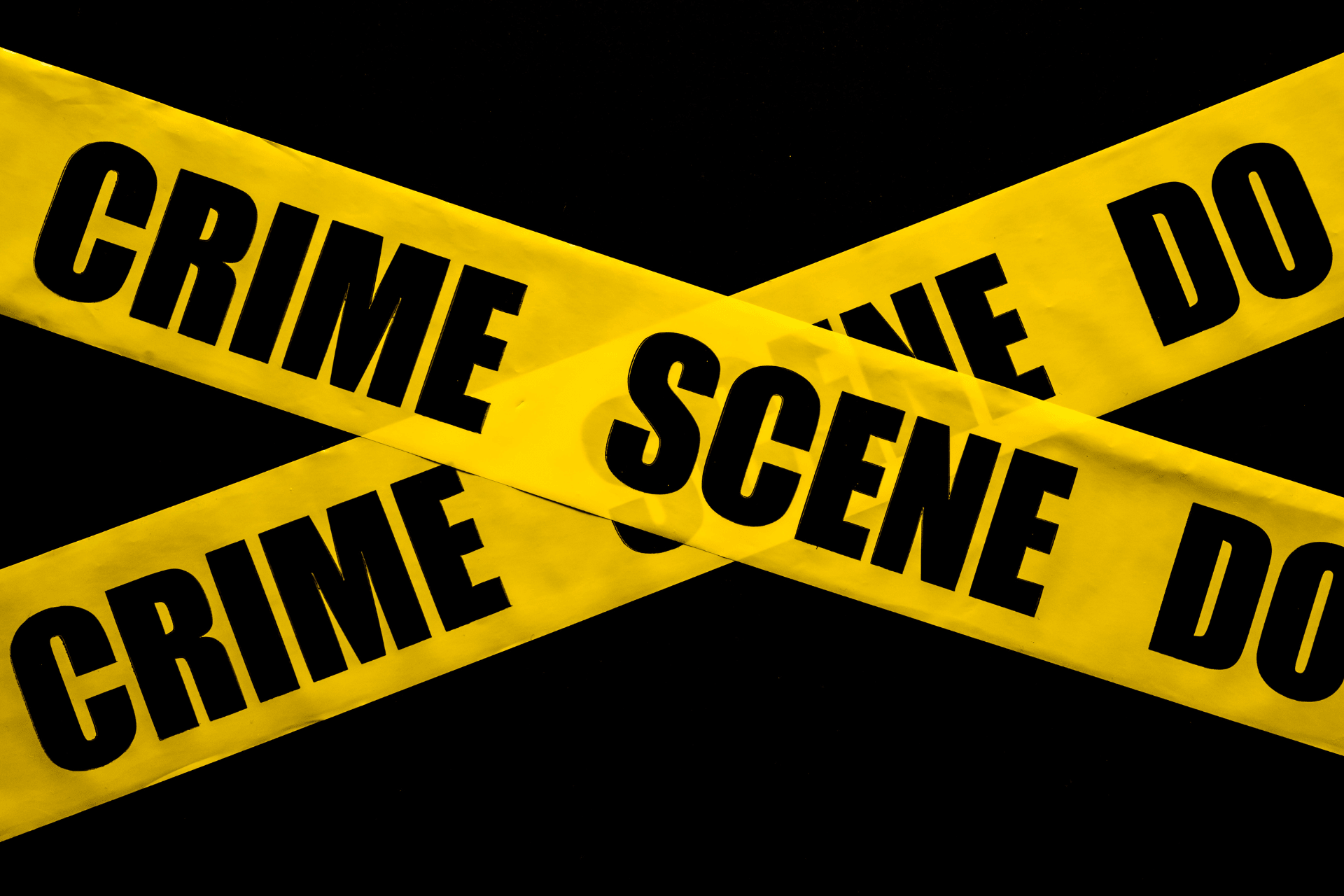 Yellow "Crime Scene Do Not Cross" tape against a dark background, illustrating the violent crime reduction operation in Cincinnati.