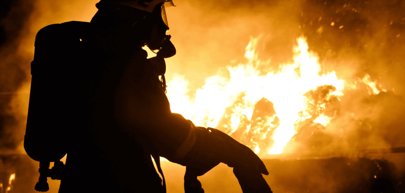 Silhouette of a firefighter standing before a large blaze, representing the 2026 volunteer firefighter shortage crisis in Ohio.