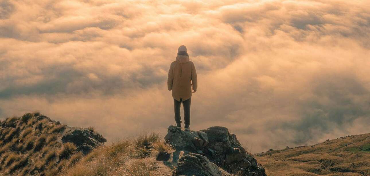 Business leader standing above the clouds at sunrise representing the agency problem and leadership in the Intelligence Age