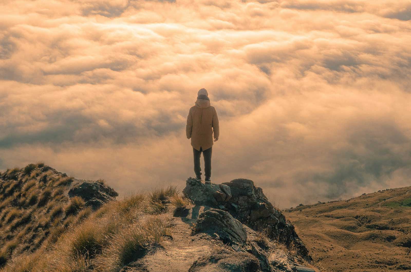 Business leader standing above the clouds at sunrise representing the agency problem and leadership in the Intelligence Age