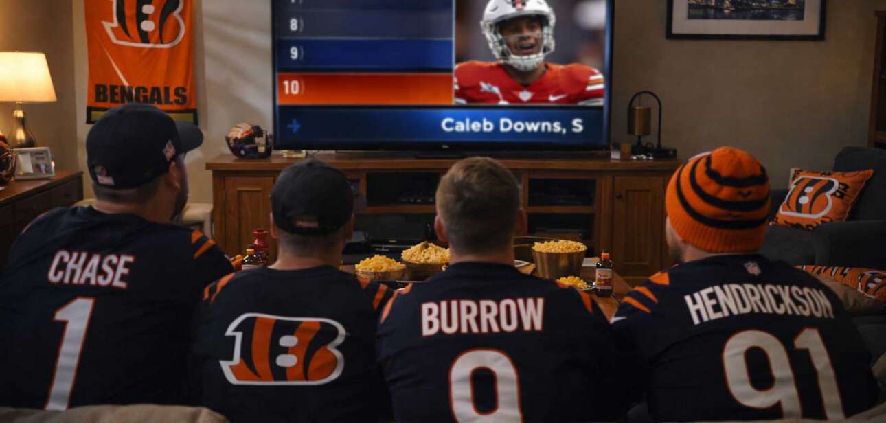 Cincinnati Bengals fans in a living room watching the 2026 NFL Draft on television as the No. 10 overall pick is announced.