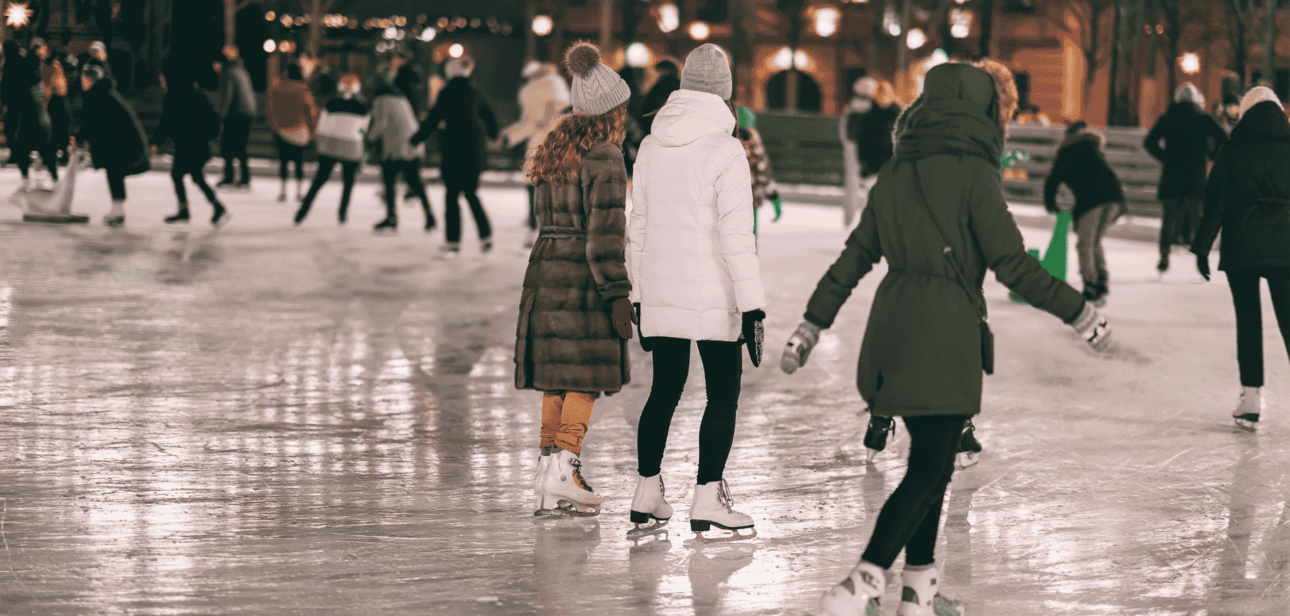 People ice skating at an outdoor rink at night under string lights in Cincinnati.