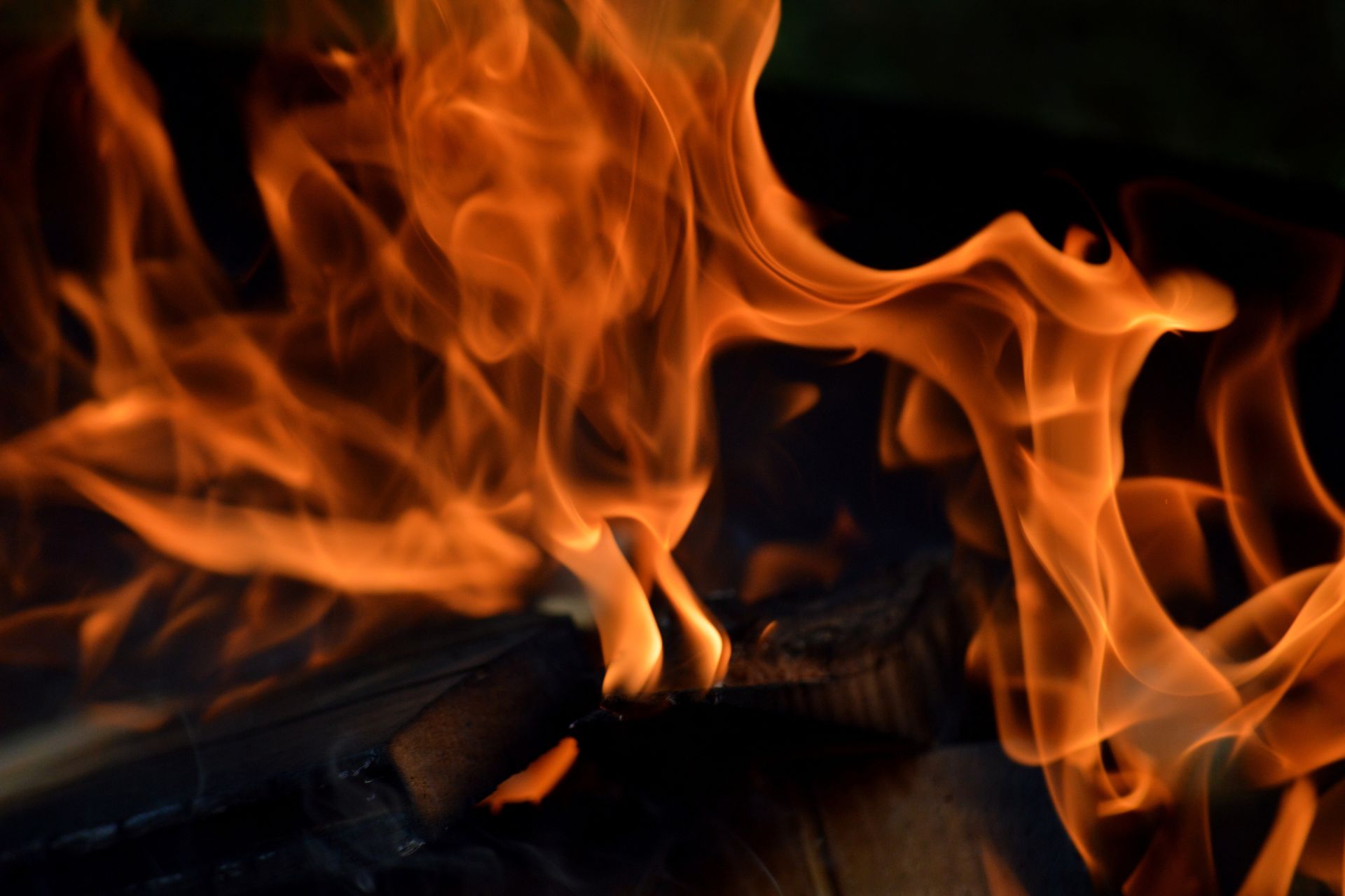 Close-up of bright orange flames burning against a dark background.