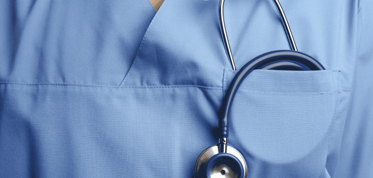 Close-up of a healthcare professional wearing blue scrubs with a stethoscope in the pocket.