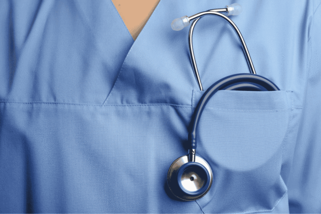 Close-up of a healthcare professional wearing blue scrubs with a stethoscope in the pocket.