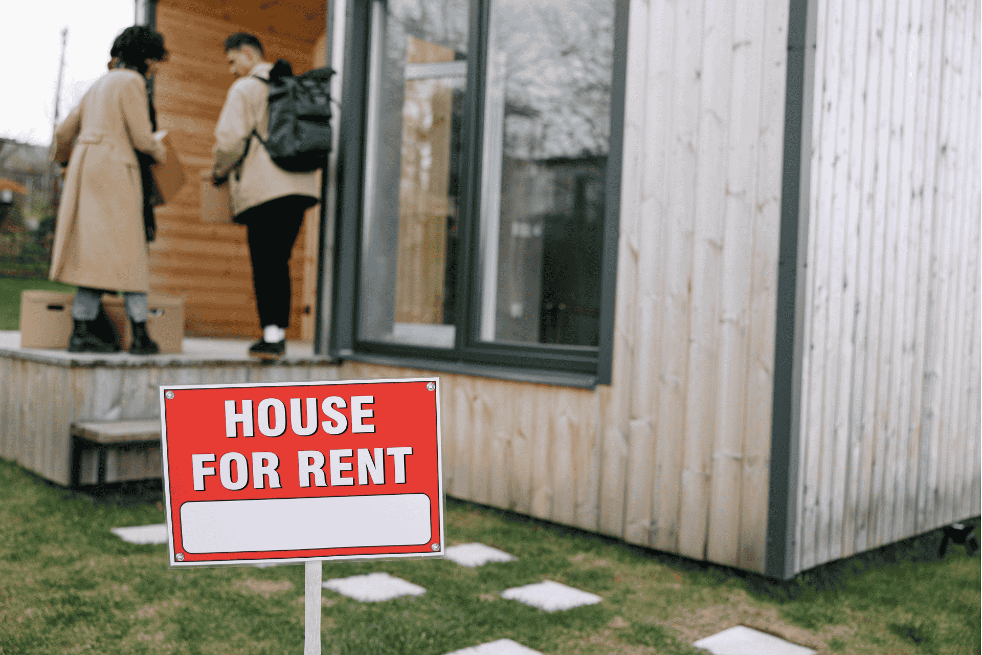 Two people looking at a modern house with a "For Rent" sign in the yard, illustrating the Cincinnati housing shortage and rental market trends.