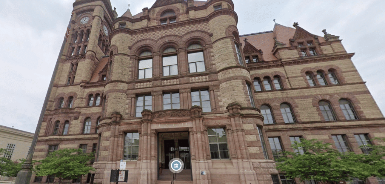Low-angle view of the Cincinnati City Hall exterior featuring red sandstone and Richardsonian Romanesque architecture.